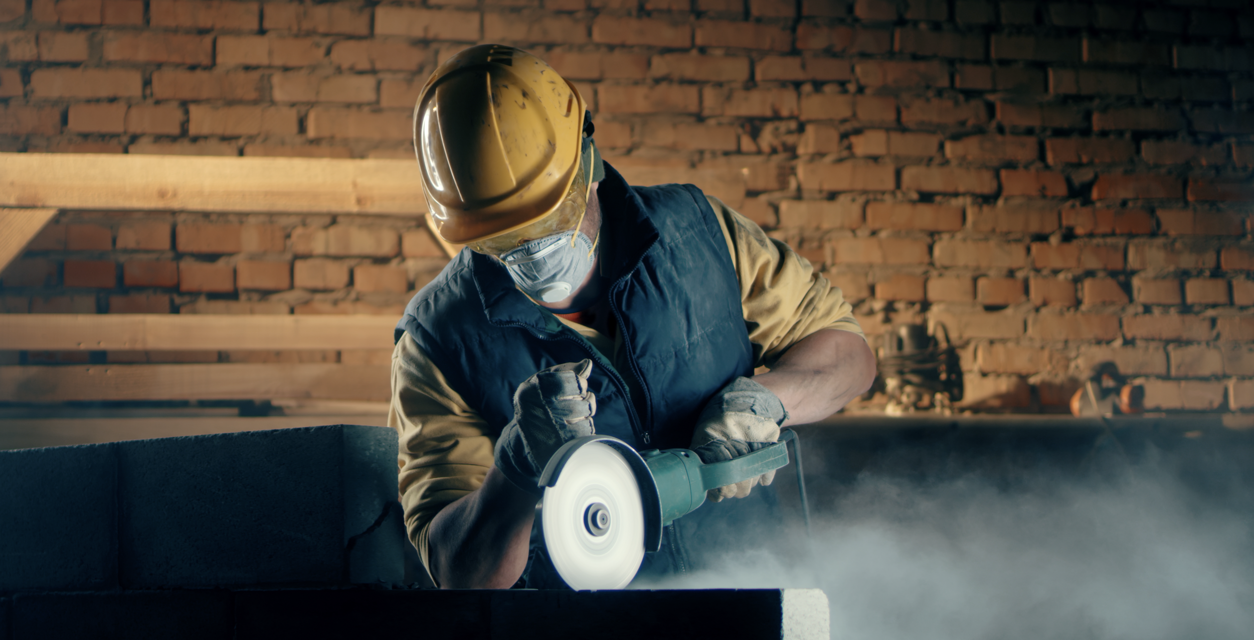 Construction worker with a mask on cutting into metal with an angle grinder for silicosis awareness